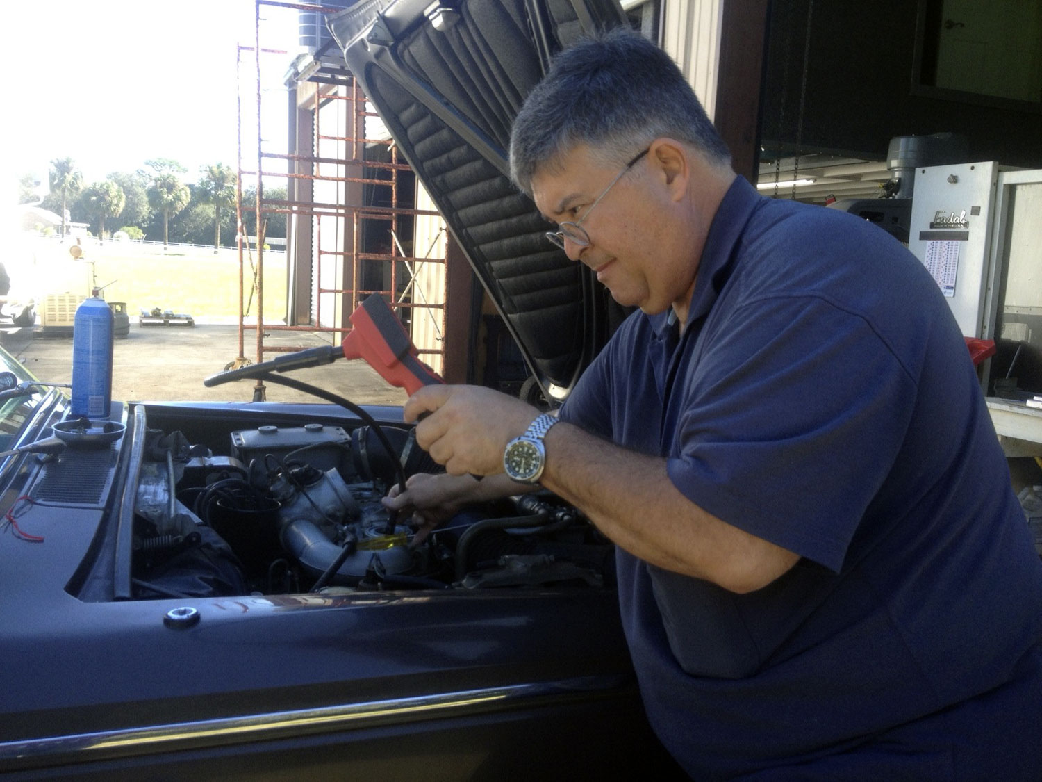 Wide angle photo of man working on old car